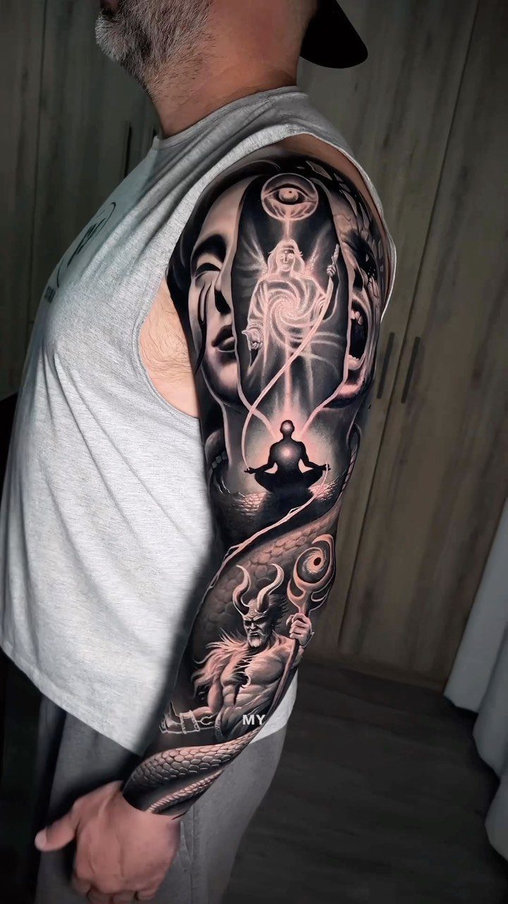 Angel and Demon Tattoo: 8 Photo Ideas for Your Next Ink 3 A detailed black and grey sleeve tattoo featuring abstract angelic and demonic figures on a man's arm.