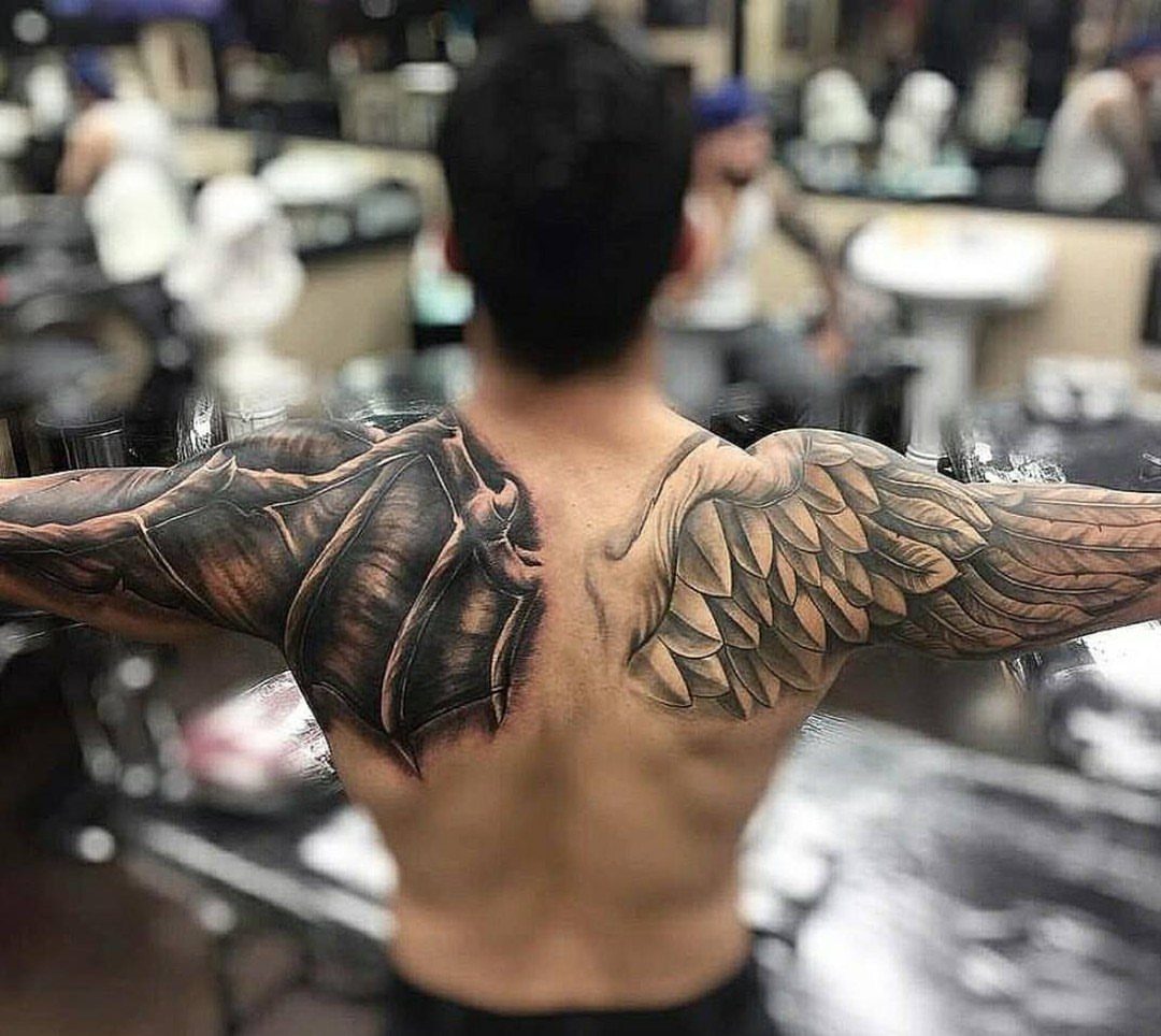 Angel and Demon Tattoo: 8 Photo Ideas for Your Next Ink 4 A man's back displaying a large tattoo of a demon wing and an angel wing.