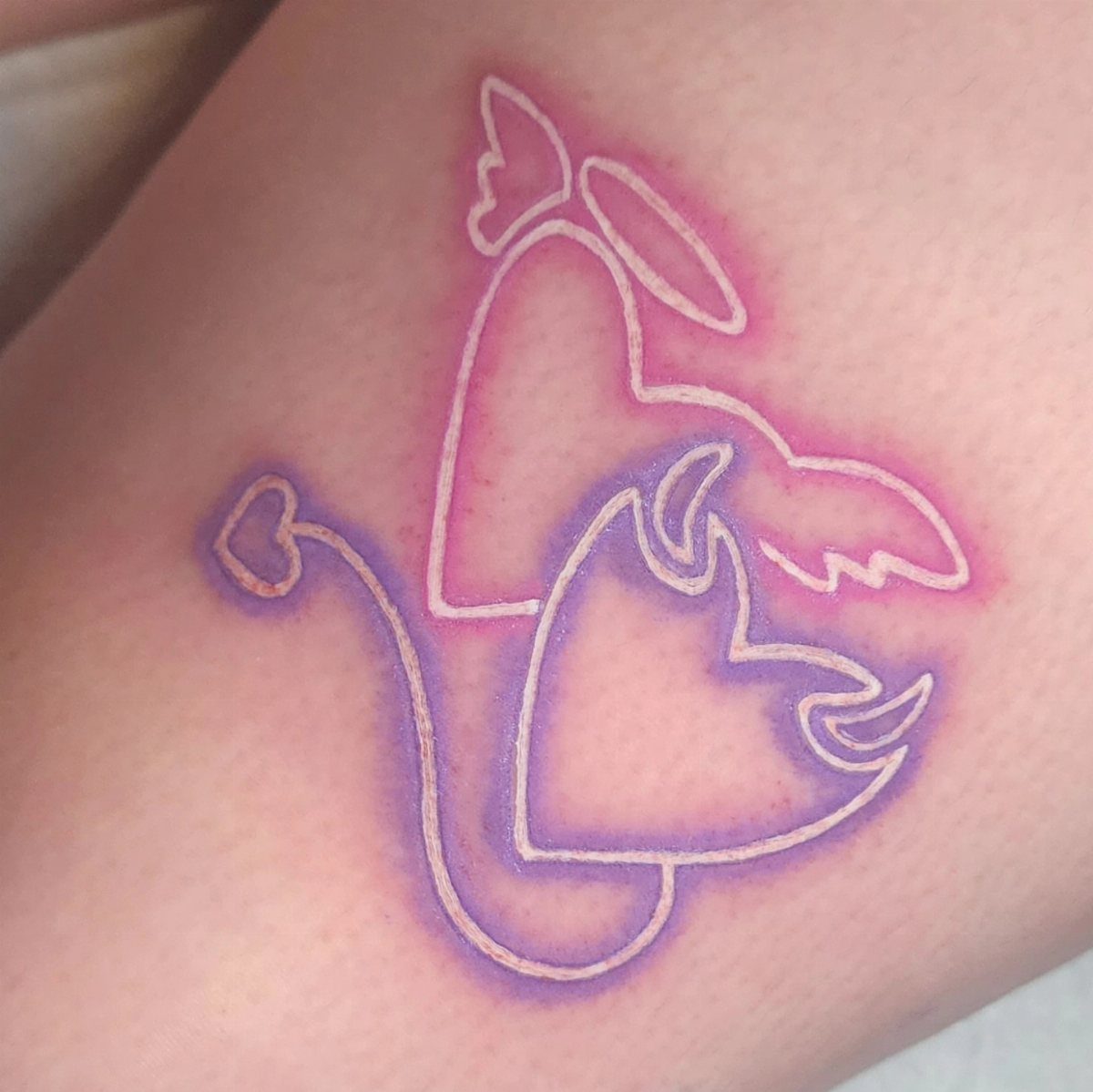 Angel and Demon Tattoo: 8 Photo Ideas for Your Next Ink 2 Minimalist angel and demon line-art tattoo forming a heart shape on skin.