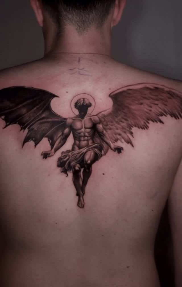 Angel and Demon Tattoo: 8 Photo Ideas for Your Next Ink 5 A large black and grey tattoo on a man's back showing a split angel and demon figure.
