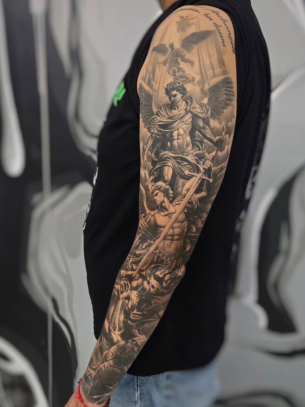 Angel and Demon Tattoo: 8 Photo Ideas for Your Next Ink 1 A detailed black and grey realism tattoo of a winged angel on a person's arm.