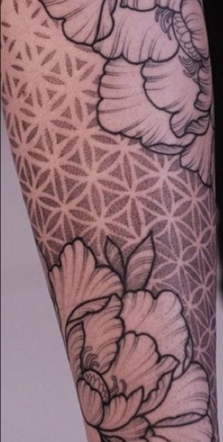 8 Arm Tattoo Filler Ideas for Sleeves That Actually Work 6 Geometric tattoo pattern of overlapping circles and triangles filling the space between large floral tattoos on an arm.