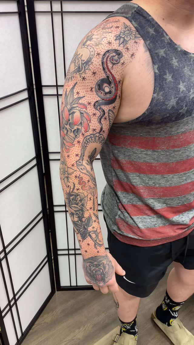 8 Arm Tattoo Filler Ideas for Sleeves That Actually Work 1 A person's arm featuring various tattoos with small dots and stars used as filler between larger designs.