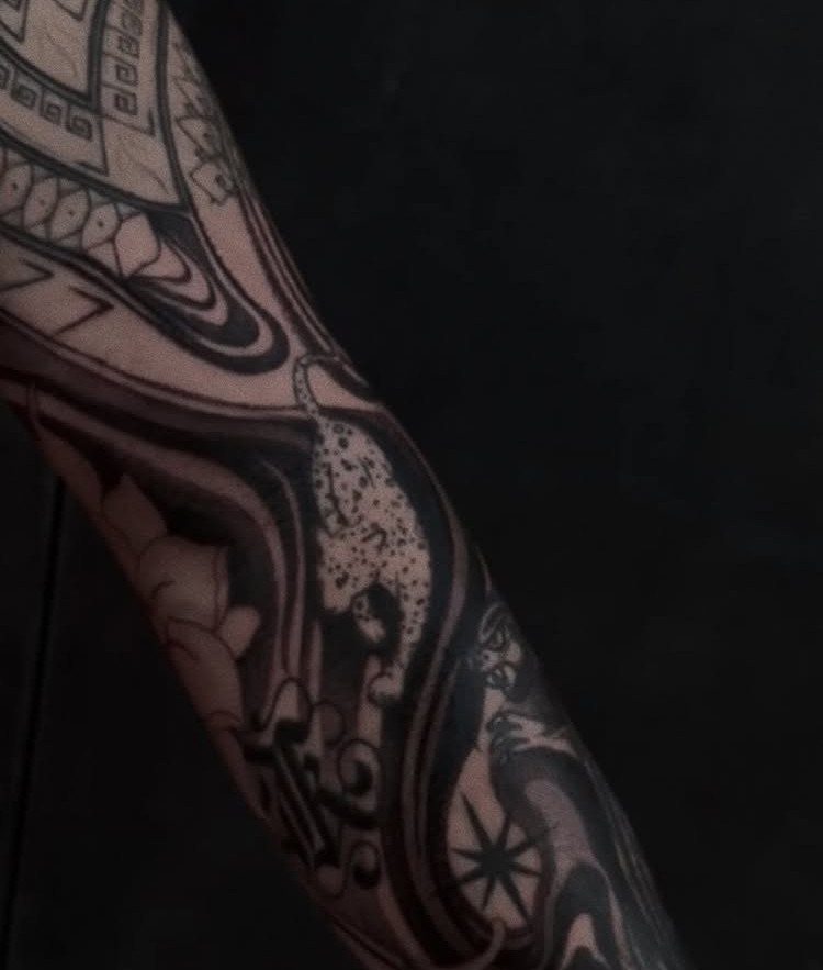 8 Arm Tattoo Filler Ideas for Sleeves That Actually Work 3 A detailed black and grey arm tattoo featuring a leopard and flowing swirling patterns.
