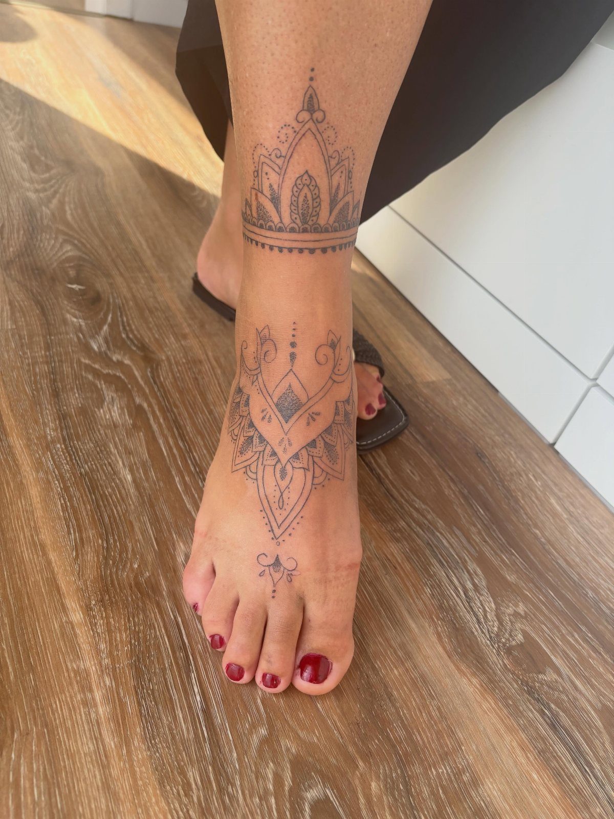 10 Around Ankle Tattoo Ideas That Follow the Body's Line 7 A person's foot and ankle decorated with intricate black ink mandala tattoos.