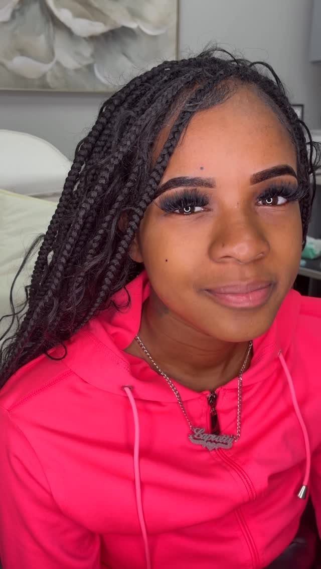 Beauty Mark Tattoo: 5 Placement Ideas for Every Face 5 A young woman with long braids and a pink hoodie looking at the camera.