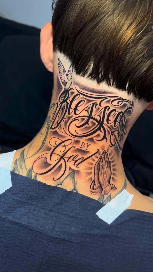 A large script tattoo on a person's neck reading Blessed by God with praying hands.