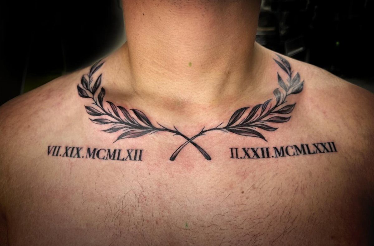 Roman numeral tattoos and laurel leaf branches on a person's collarbone area.