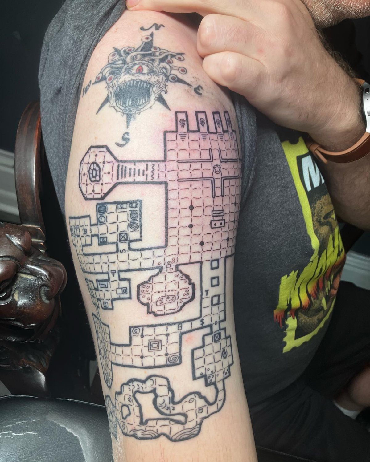 D&D Magic Tattoo Ideas: 9 Designs for Every Player 4 A large black ink tattoo of a detailed dungeon map covering a person's upper arm.