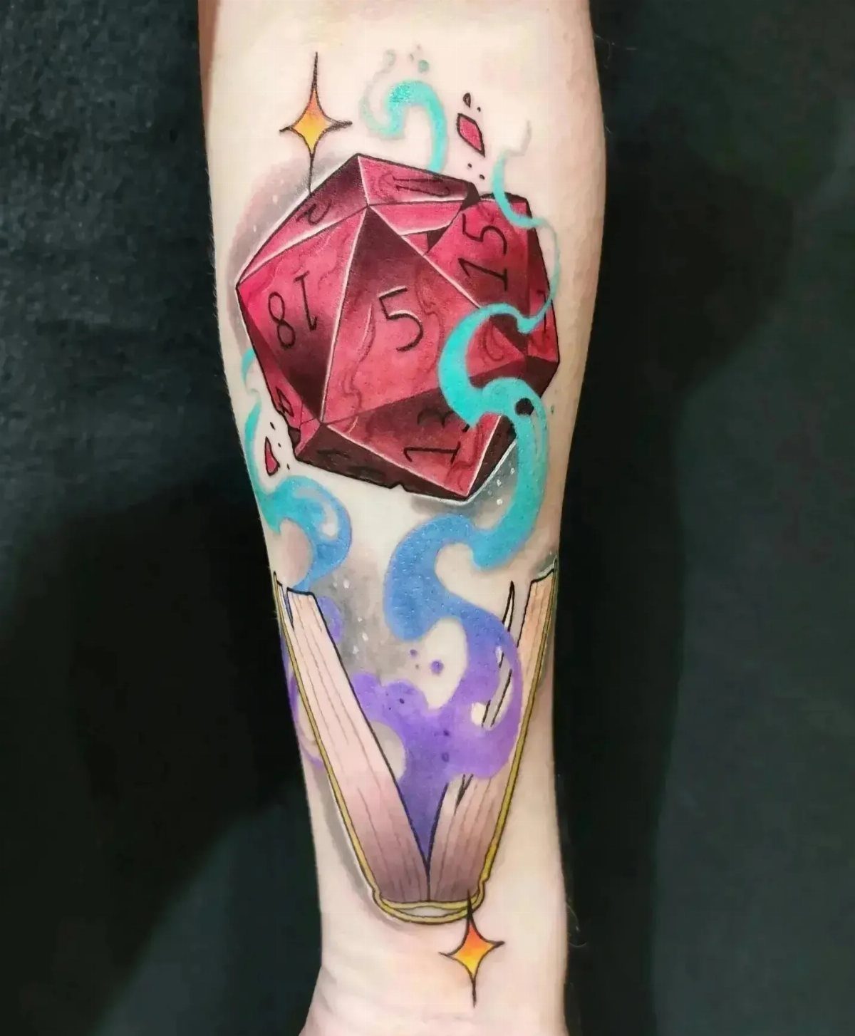 D&D Magic Tattoo Ideas: 9 Designs for Every Player 2 A colorful tattoo of a red twenty-sided die floating above an open book with magical swirls.