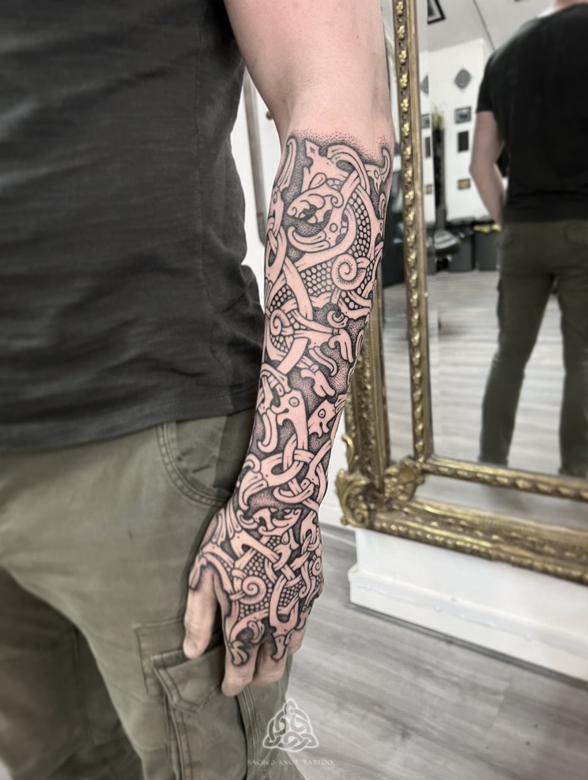 D&D Magic Tattoo Ideas: 9 Designs for Every Player 1 A person's arm and hand covered in a detailed Nordic style knotwork tattoo.