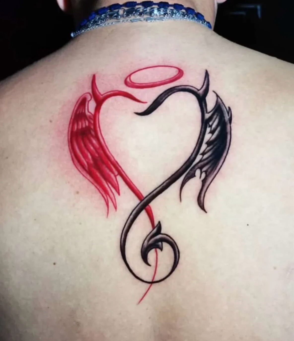 6 Evil Angel Tattoo Design Ideas and Inspiration 5 A heart-shaped tattoo on a back composed of a red angel wing and a black devil wing.