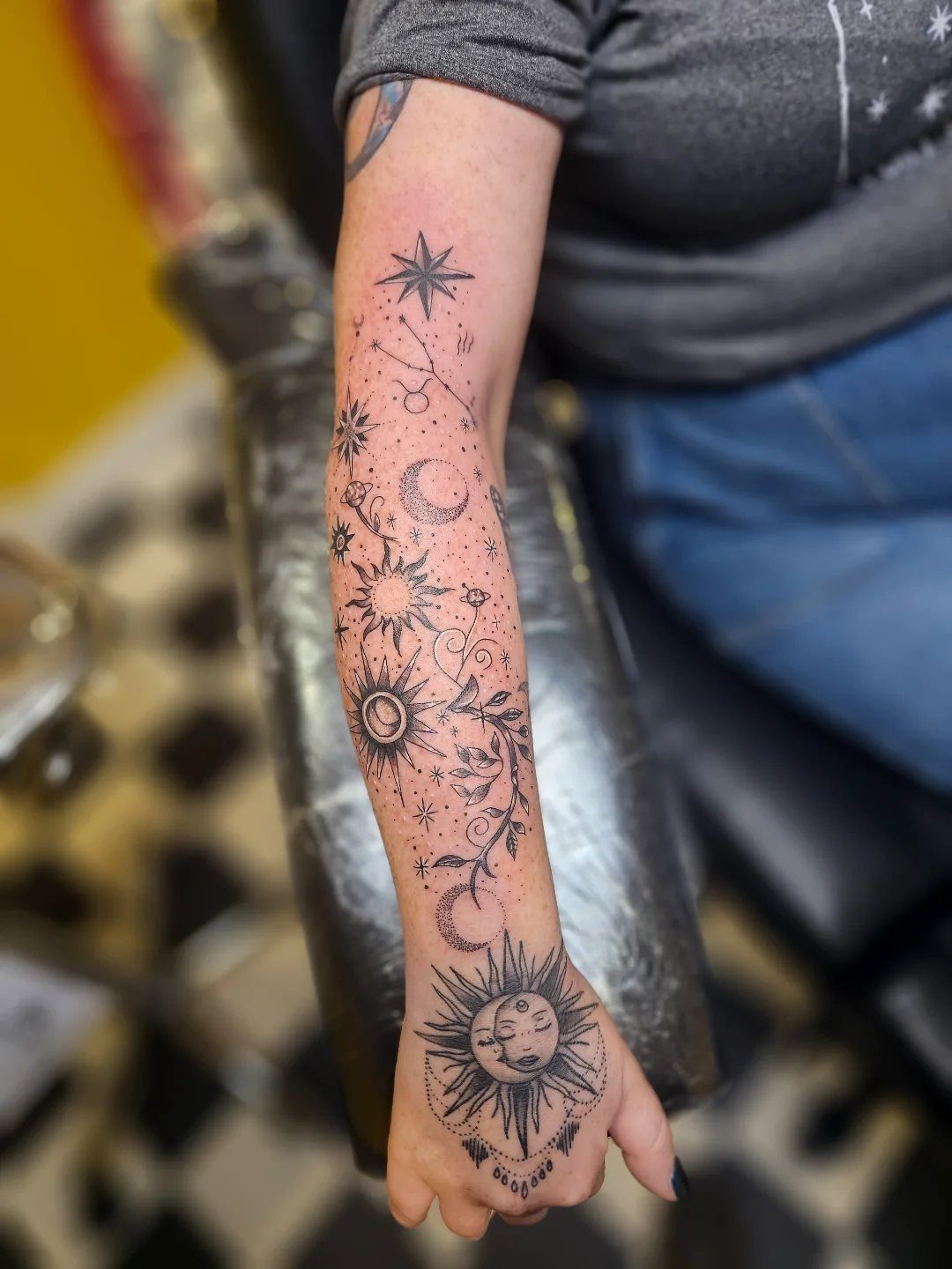 Fine Line Tattoo Sleeve: 10 Ideas With Photos 2 A person's arm displaying a fine line tattoo sleeve with celestial sun, moon, and star designs.