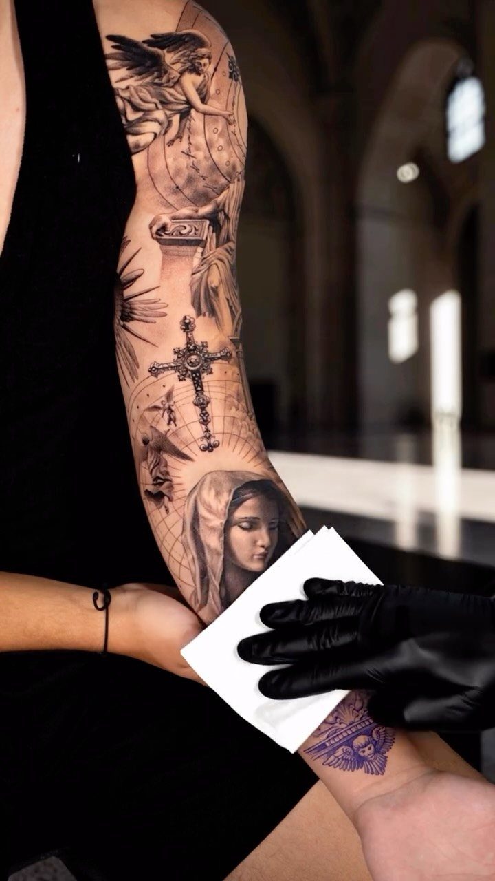 Fine Line Tattoo Sleeve: 10 Ideas With Photos 6 A detailed black and grey religious themed tattoo sleeve on a person's arm.