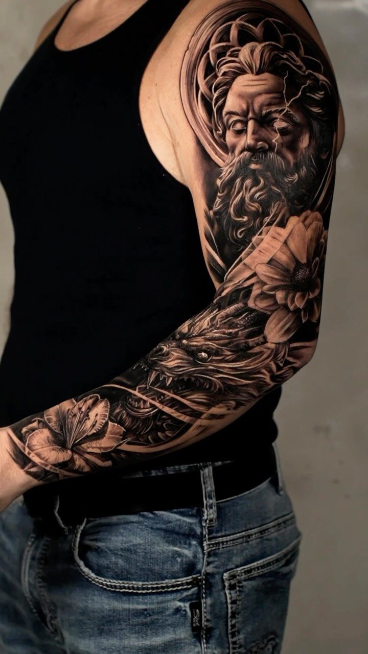 Good vs Evil Tattoo: 8 Designs That Split Skin Between Sides 6 A detailed black and grey realism tattoo on a man's arm featuring a bearded man and a monster.