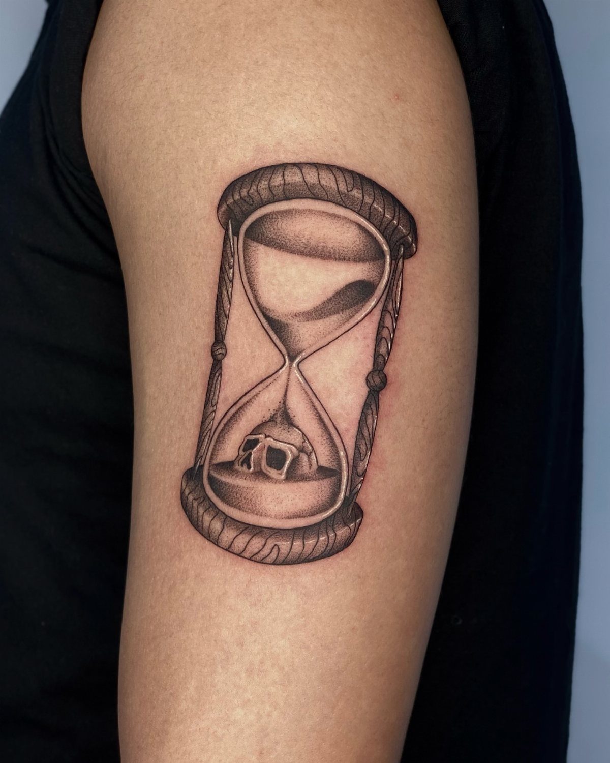 Hour Glass Tattoo Ideas: 12 Designs for Every Style 5 A black and grey realism tattoo of an hourglass containing a small skull in the bottom bulb.
