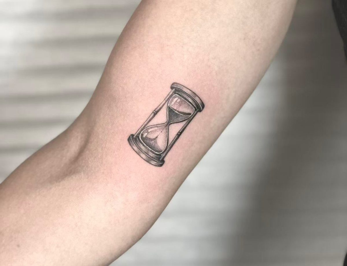 Hour Glass Tattoo Ideas: 12 Designs for Every Style 1 A minimalist black ink hourglass tattoo on a person's forearm skin.