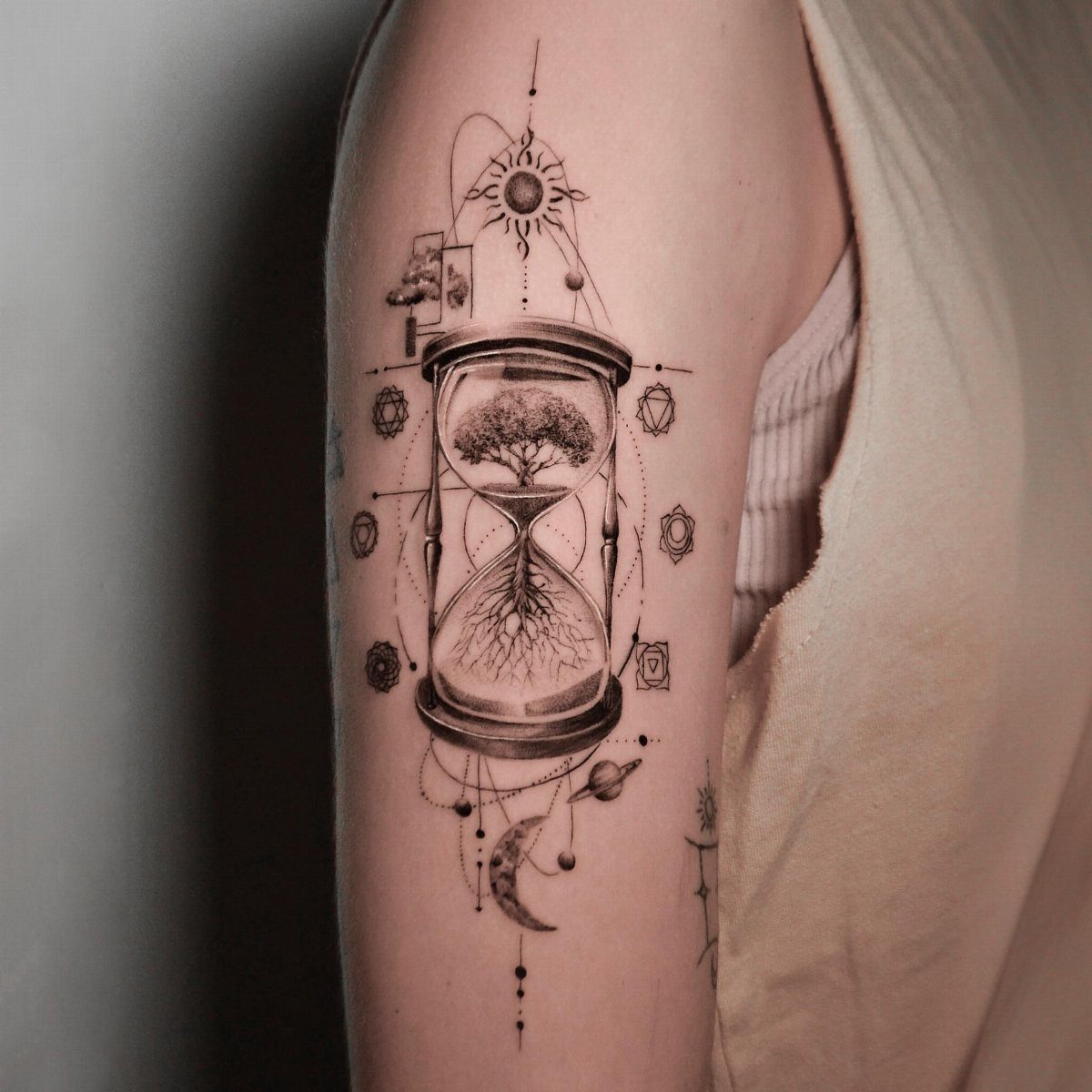 Hour Glass Tattoo Ideas: 12 Designs for Every Style 10 A detailed black ink tattoo of an hourglass containing a tree on a person's arm.