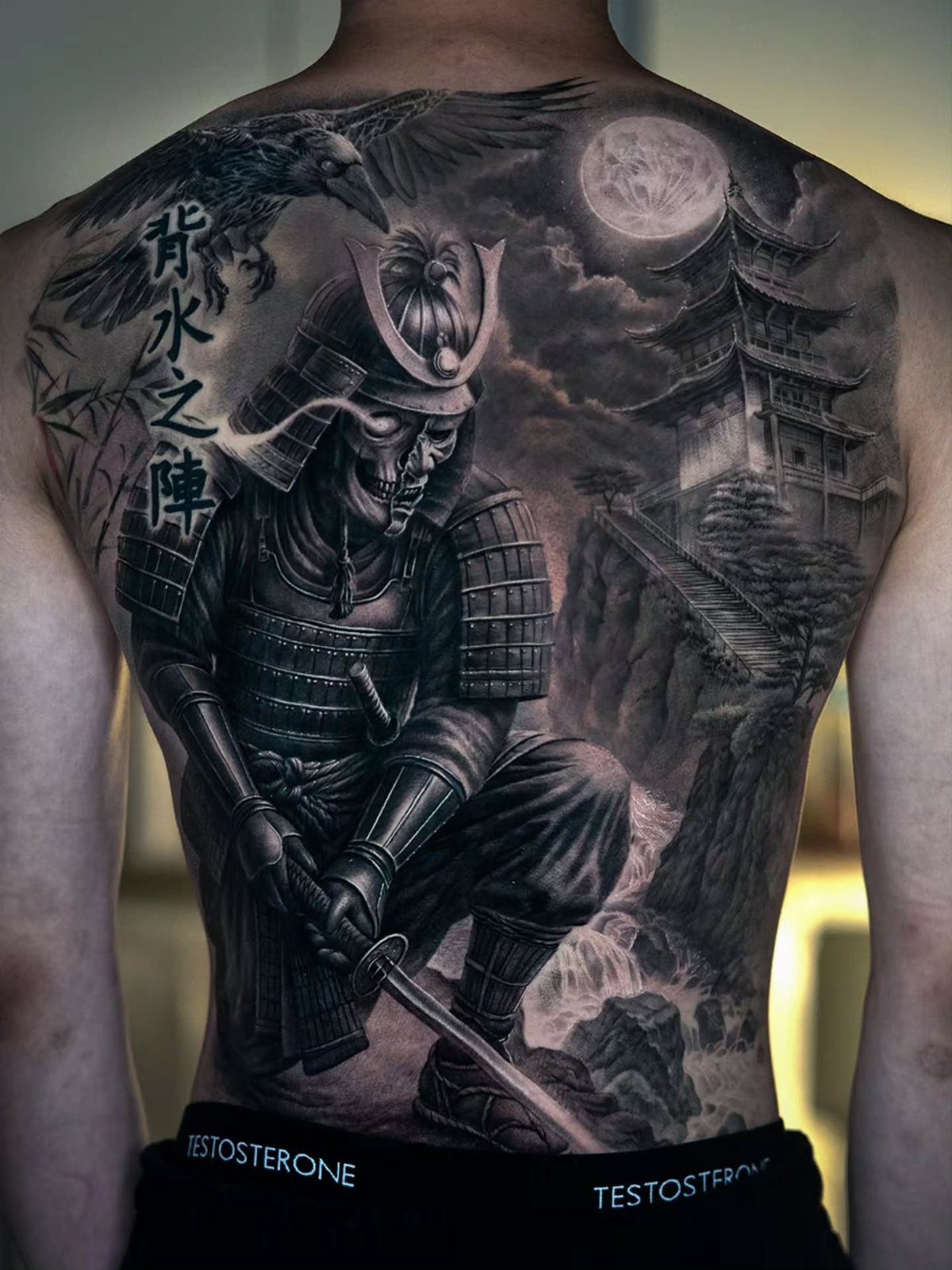 A detailed black and grey back tattoo of a samurai in a landscape with a pagoda.