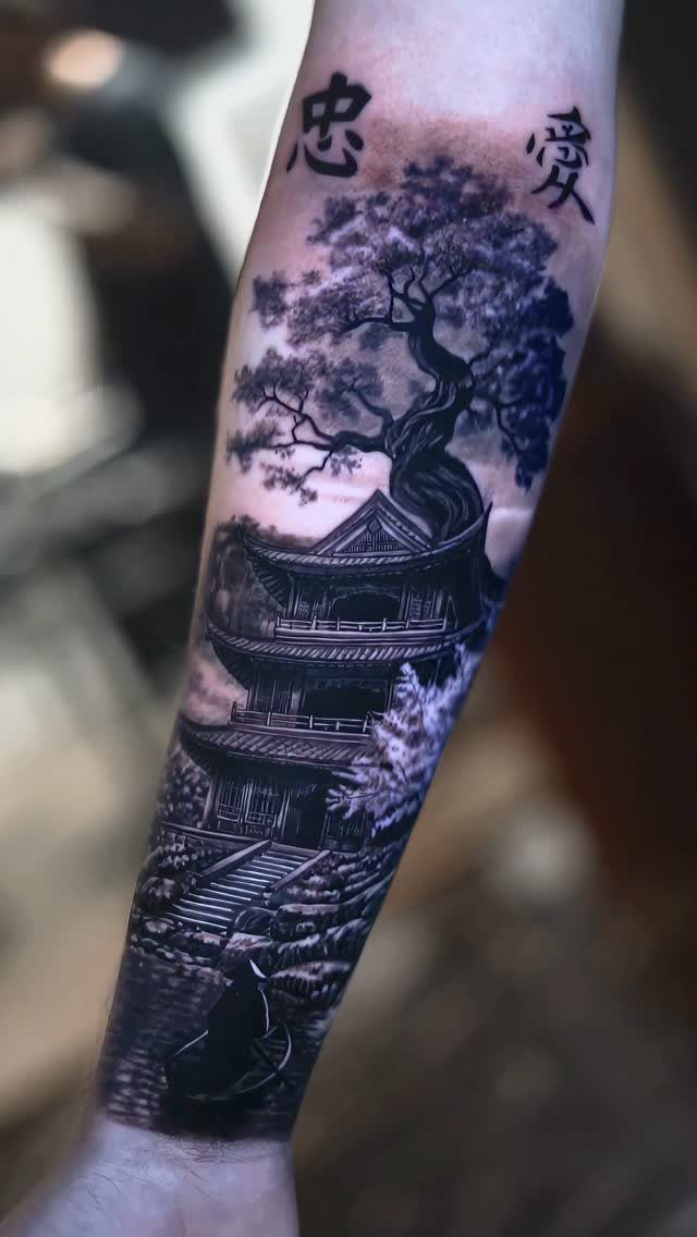 A detailed black and grey tattoo of a Japanese pagoda and tree on a forearm.