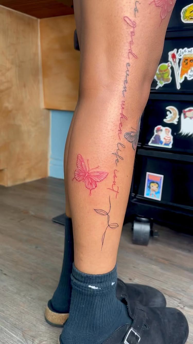 5 Leg Tattoo Template Ideas: From Printable to Full Leg Sleeve 4 A person's leg decorated with red butterfly and script tattoos, wearing black socks and shoes.