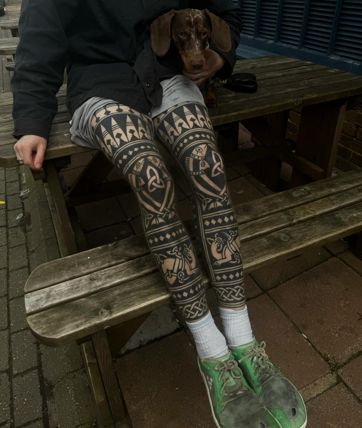 Man Leg Tattoo: 8 Styles That Fill the Canvas From Hip to Ankle 7 A person's legs covered in large black ink geometric and knotwork tattoos sitting on a bench.