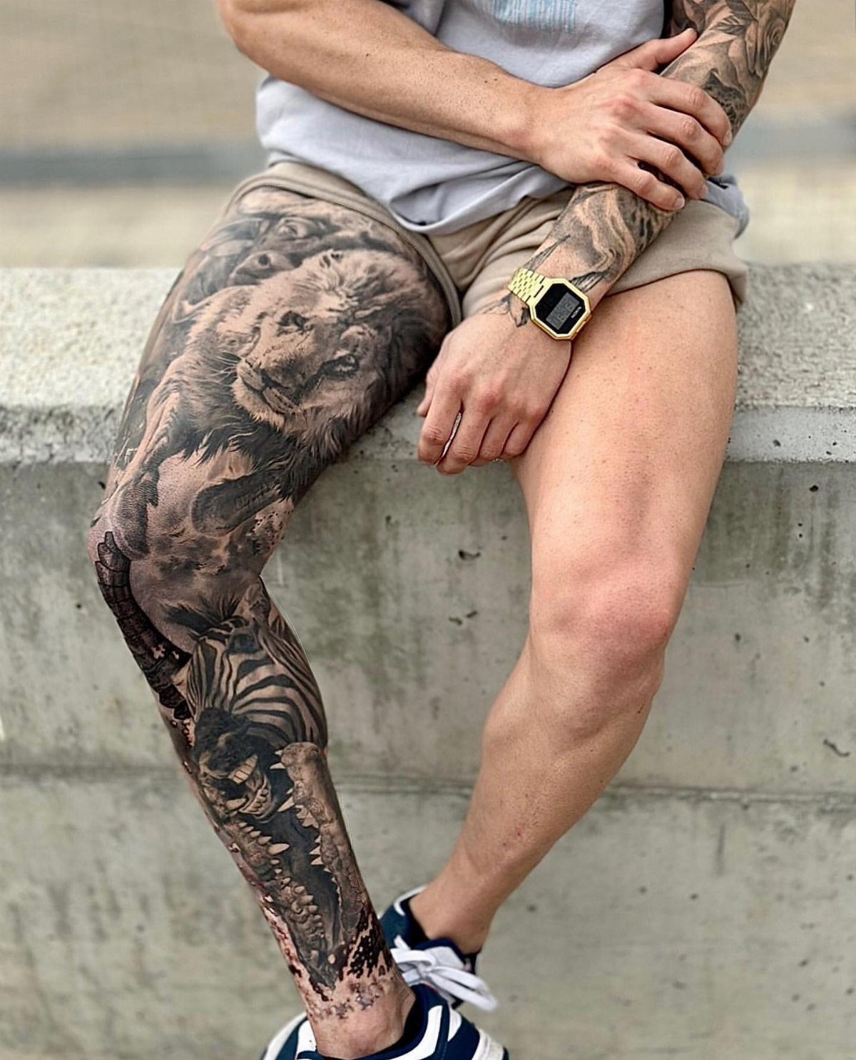 Man Leg Tattoo: 8 Styles That Fill the Canvas From Hip to Ankle 6 A man's leg featuring a large black and grey realism tattoo of a lion and zebra.