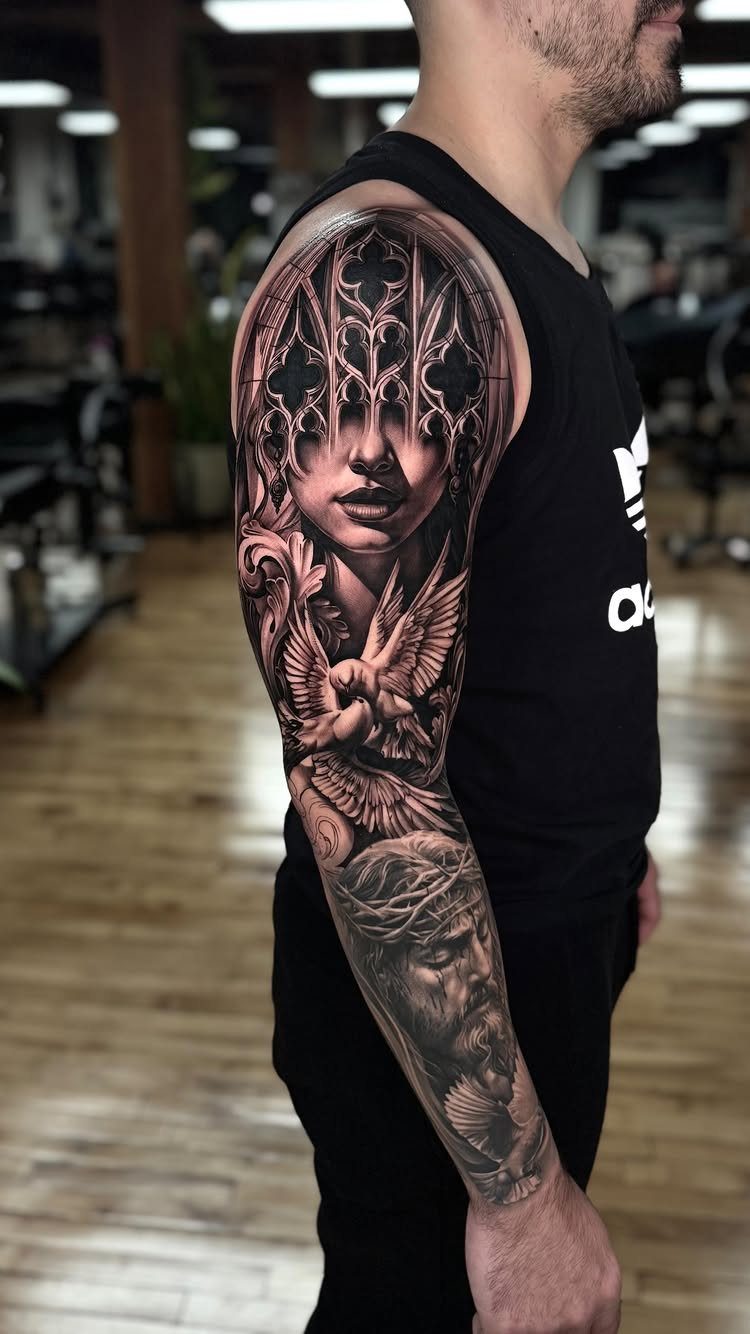 A man's arm displaying a detailed black and grey sleeve tattoo featuring a woman's face and gothic patterns.