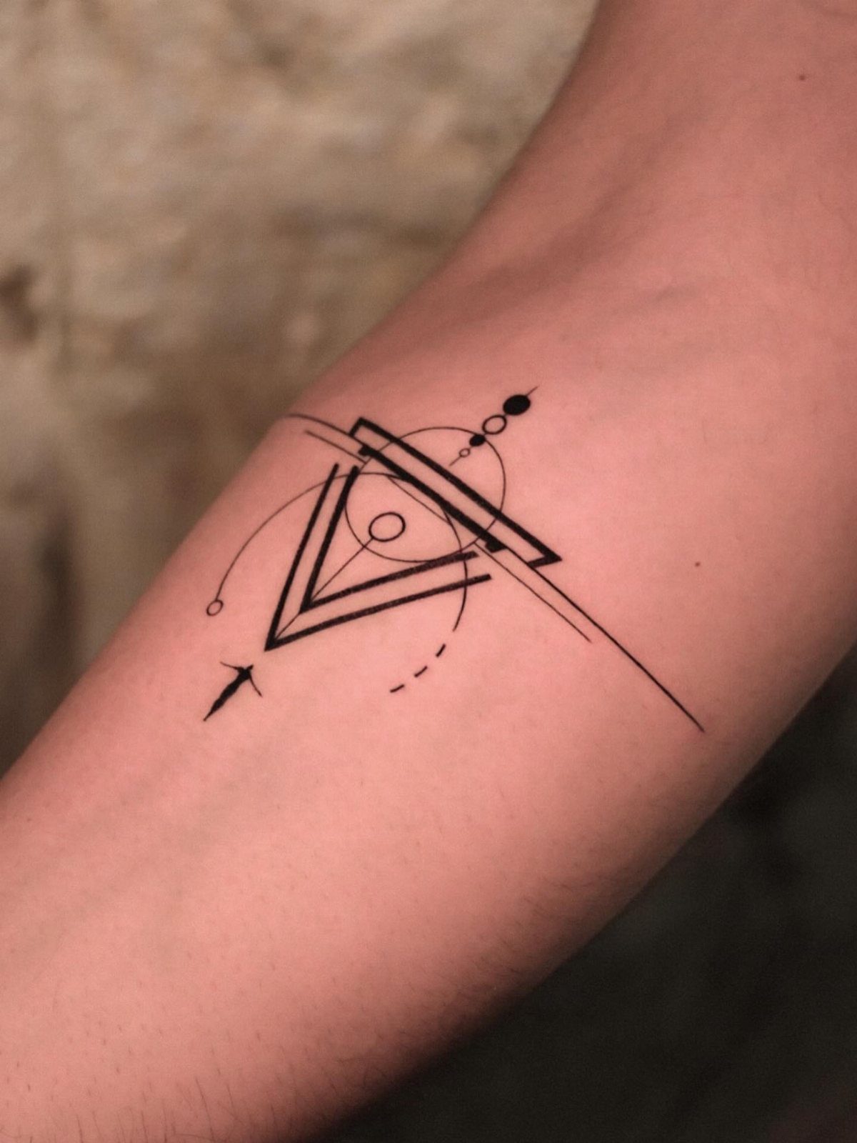 14 Minimalist Tattoo Design Ideas That Stay Simple and Clean 1 A geometric minimalist tattoo with triangles and lines on a person's arm.