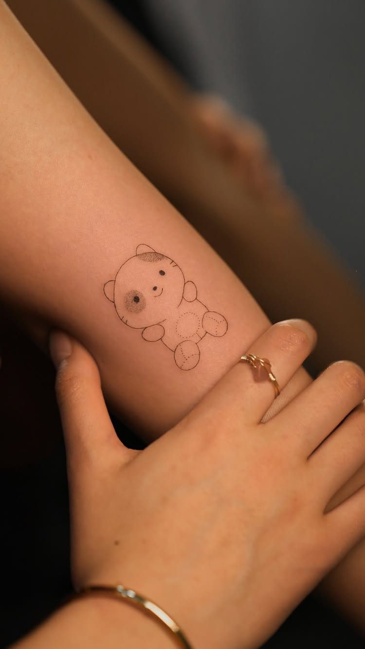 14 Minimalist Tattoo Design Ideas That Stay Simple and Clean 12 A small minimalist panda bear tattoo on a person's arm.