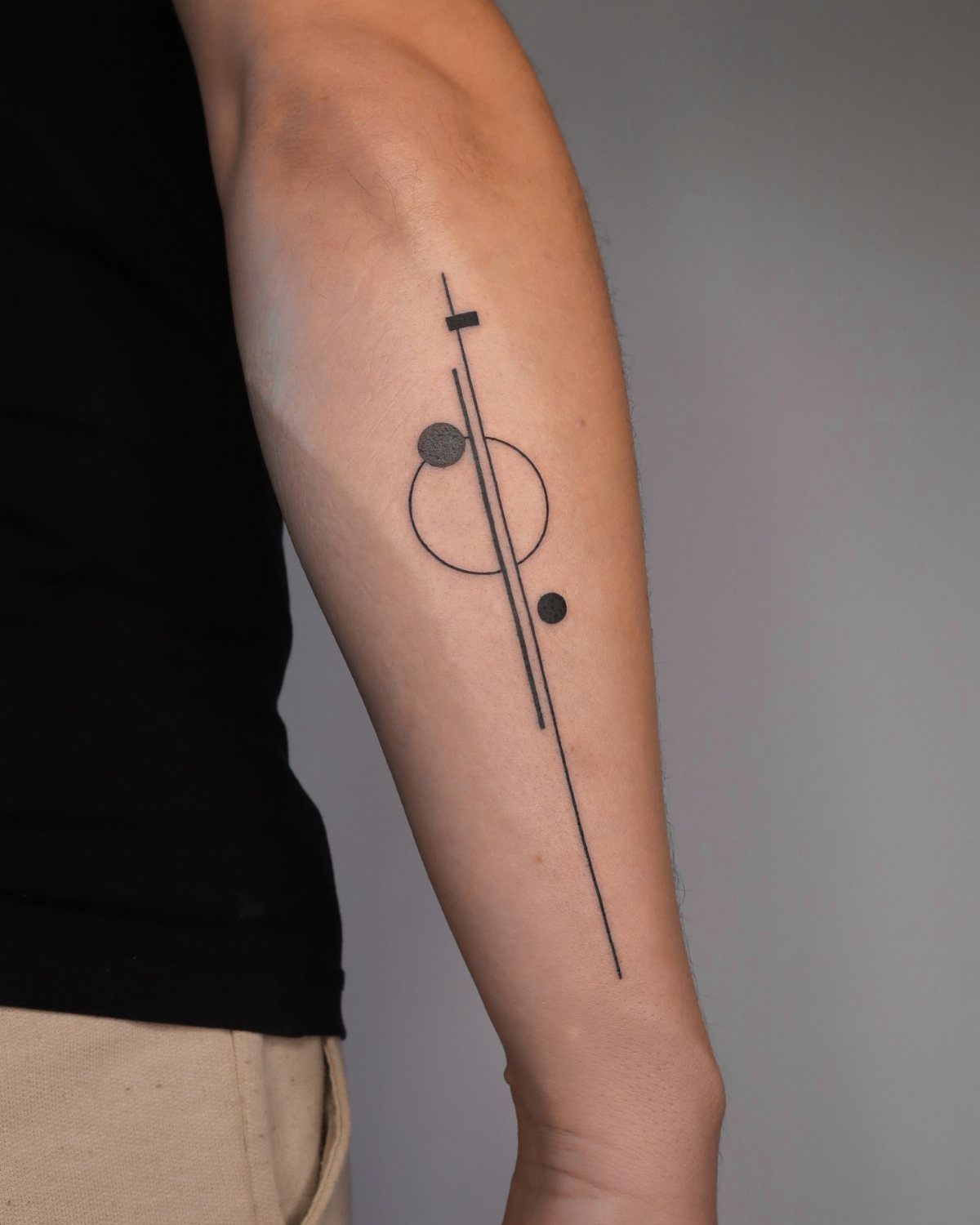 14 Minimalist Tattoo Design Ideas That Stay Simple and Clean 2 A minimalist black ink line art tattoo on a person's arm featuring geometric shapes.