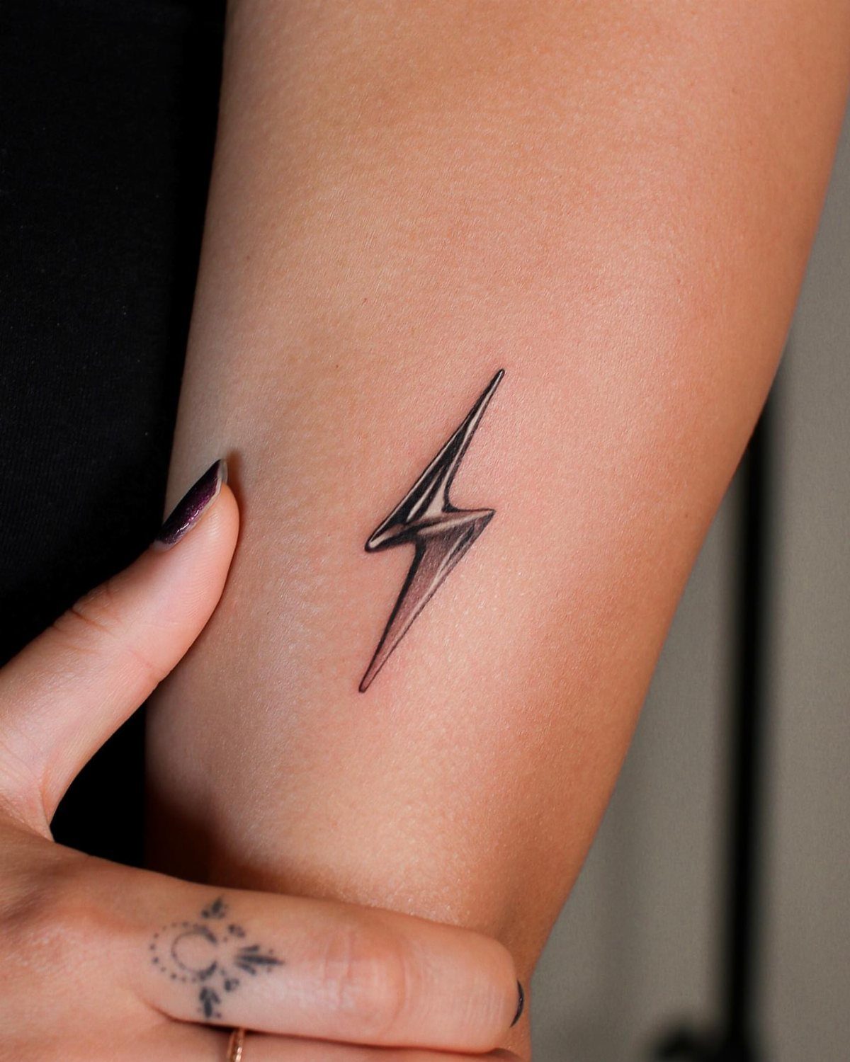 14 Minimalist Tattoo Design Ideas That Stay Simple and Clean 11 A minimalist black ink lightning bolt tattoo on a person's forearm skin.