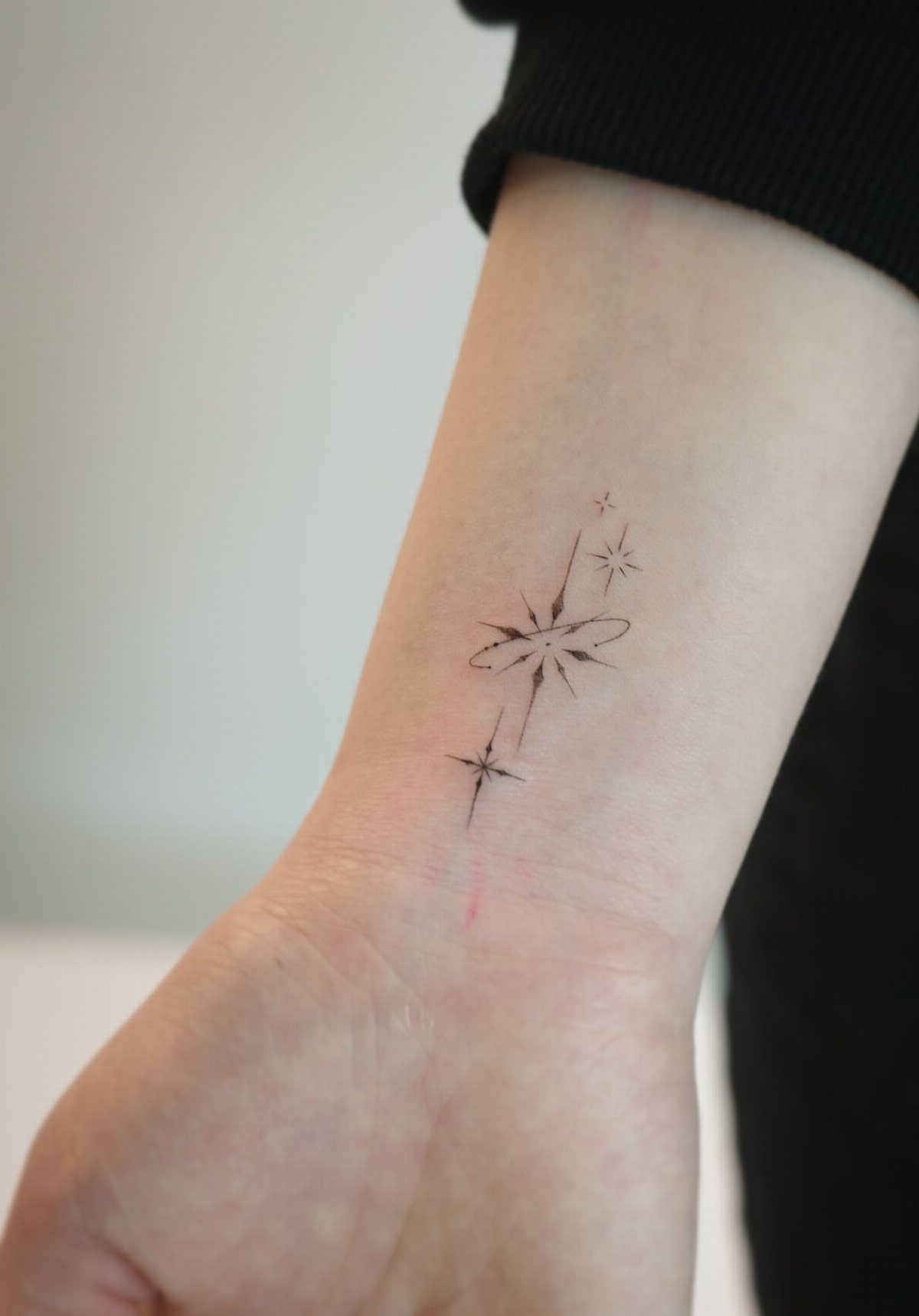 14 Minimalist Tattoo Design Ideas That Stay Simple and Clean 6 Small fine-line star tattoos on a person's inner wrist against a neutral background.