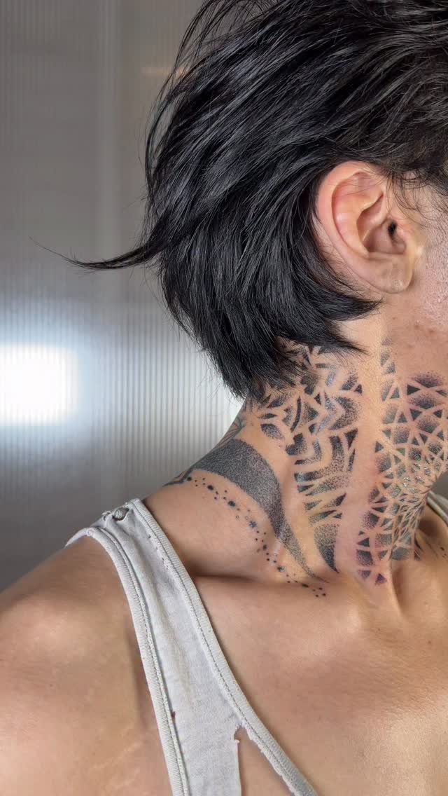 7 Neck Tattoo Designs for Women That Actually Fit the Narrow Canvas 3 A person with short dark hair displaying large black geometric pattern tattoos on their neck.