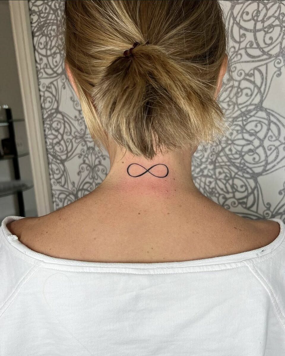 7 Neck Tattoo Designs for Women That Actually Fit the Narrow Canvas 6 A small black infinity symbol tattoo on the back of a woman's neck.