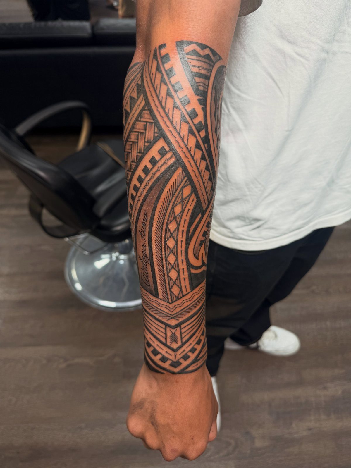 Sick Tattoo Art: 9 Styles That Redefine the Needle 3 A detailed black ink tribal tattoo with geometric patterns covering a person's forearm.