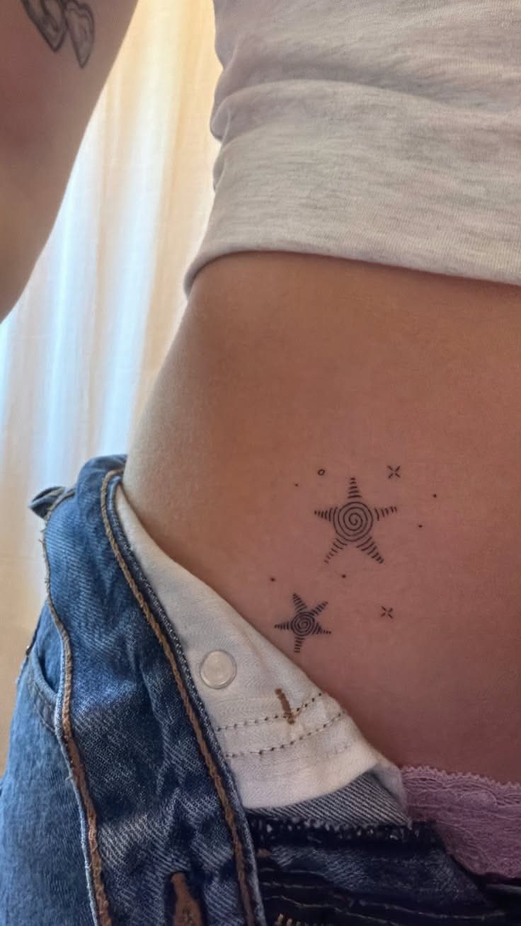 Star Tattoo on Hip: 6 Fresh Ideas for Placement and Style 4 Two small fine-line star tattoos on a person's hip near the waistline.