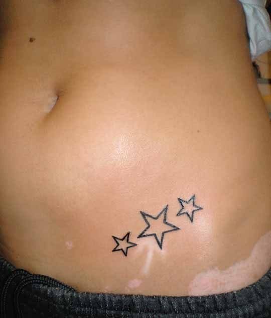 Star Tattoo on Hip: 6 Fresh Ideas for Placement and Style 1 Three small black ink outline stars tattooed diagonally on a person's hip.