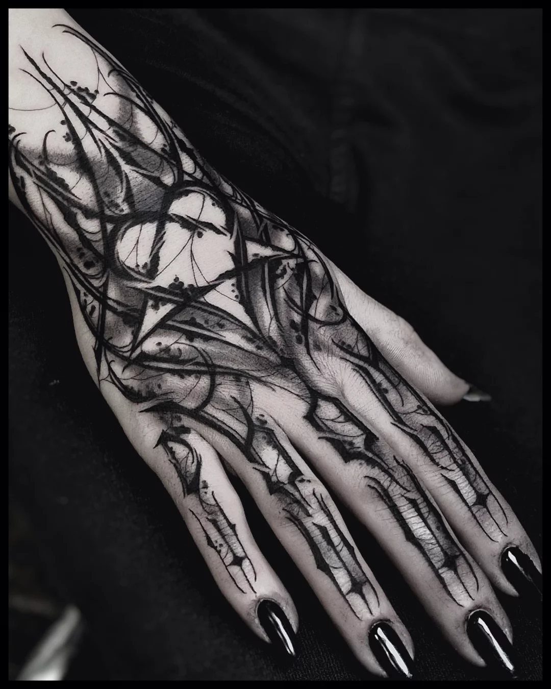 Stencil Tattoo Ideas: 14 Designs for Artists and First-Timers 4 A hand with a detailed blackwork tattoo featuring bold, abstract flowing lines and patterns.