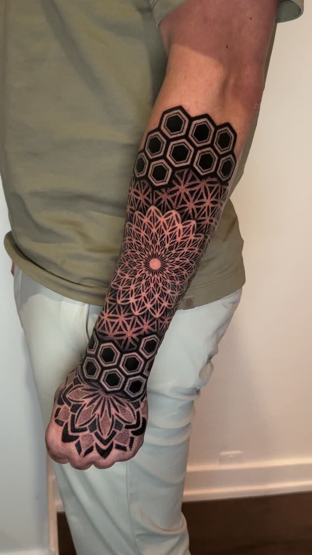Stencil Tattoo Ideas: 14 Designs for Artists and First-Timers 2 A person's arm displaying a large black geometric tattoo with mandala and hexagon patterns.