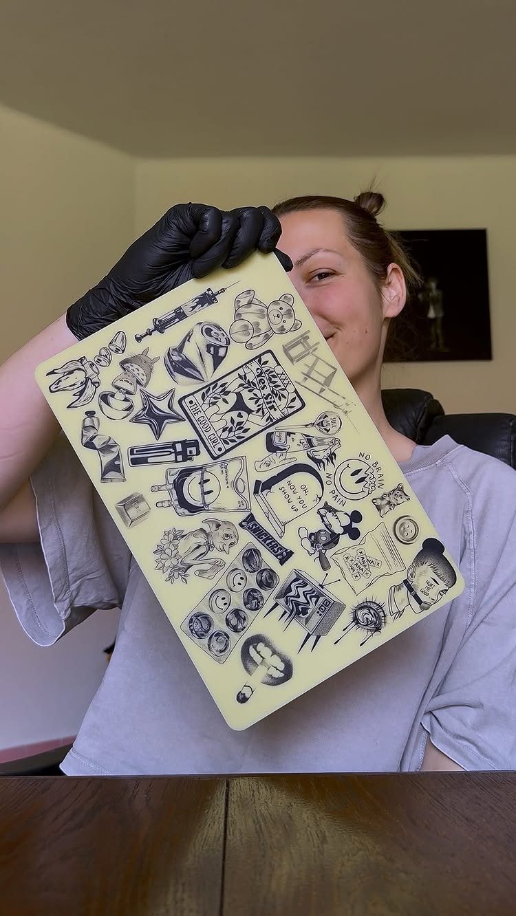Stencil Tattoo Ideas: 14 Designs for Artists and First-Timers 13 A person holding a yellow sheet displaying numerous black ink stencil tattoo designs.