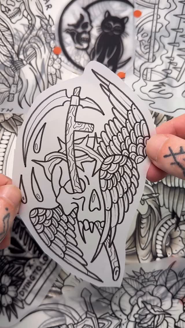 Stencil Tattoo Ideas: 14 Designs for Artists and First-Timers 3 Hands holding a translucent stencil paper featuring a winged skull and scythe tattoo design.