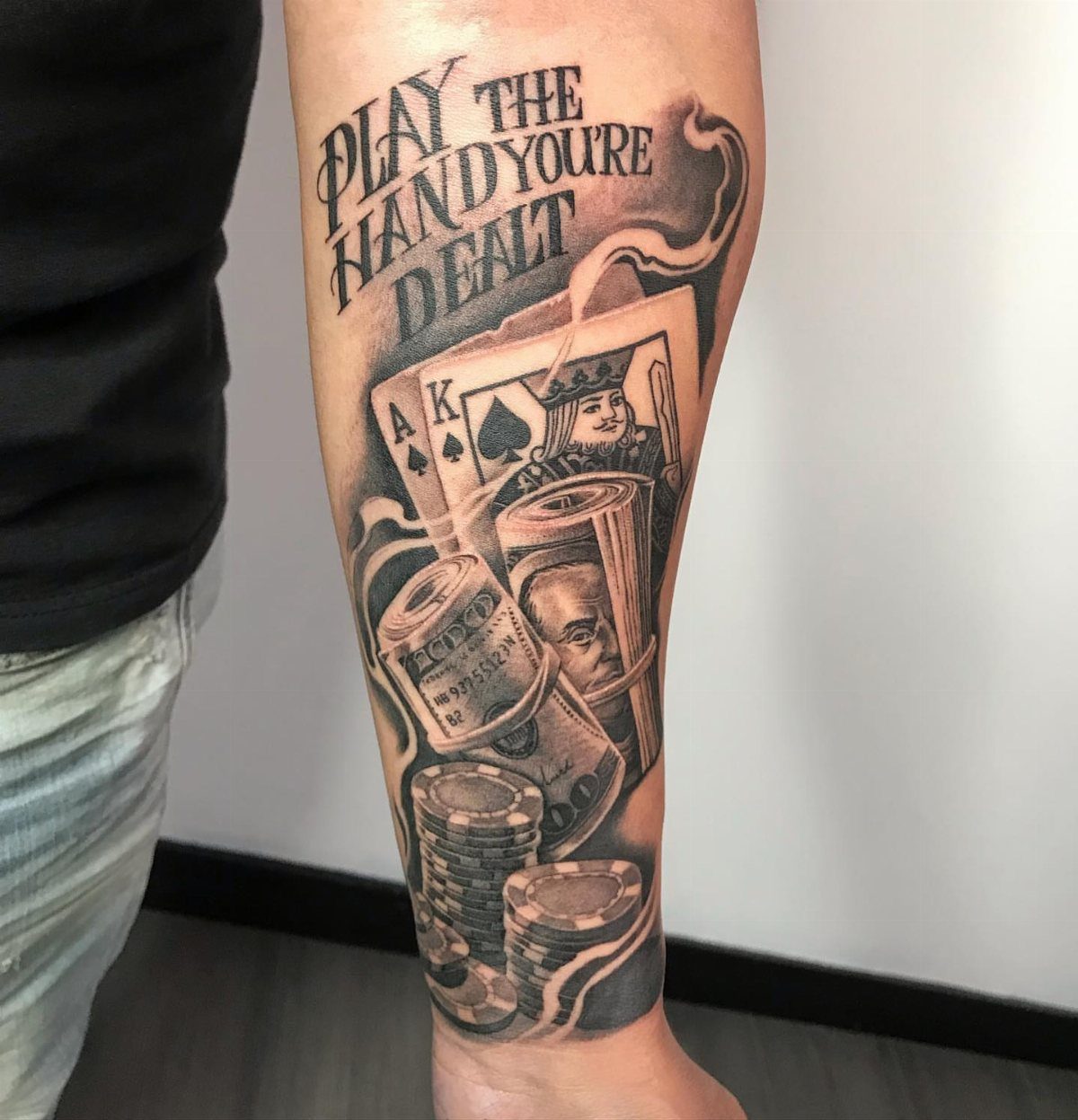 Black and grey tattoo on a leg featuring playing cards, money, and poker chips.
