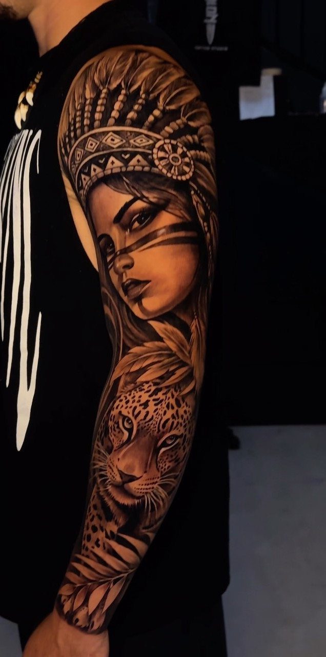 A detailed black and grey realism tattoo of a woman in a headdress and a leopard on a man's arm.