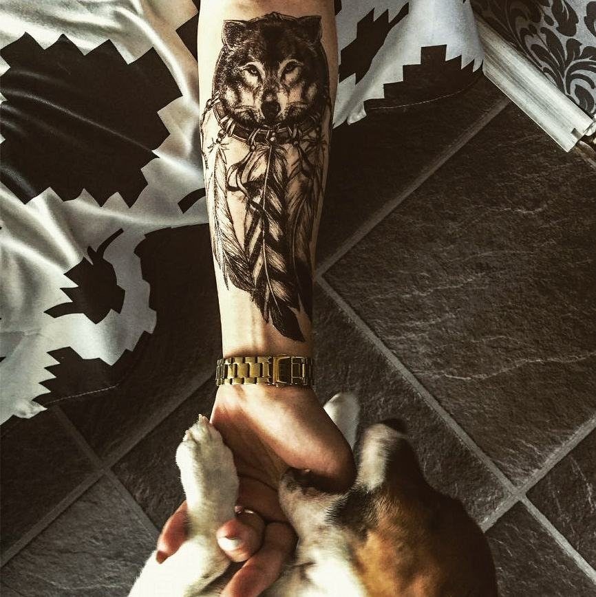 Tattoo Pattern for Beginners: 6 Starter Designs to Trace First 4 A wolf head tattoo with feathers on a person's forearm holding a small dog.