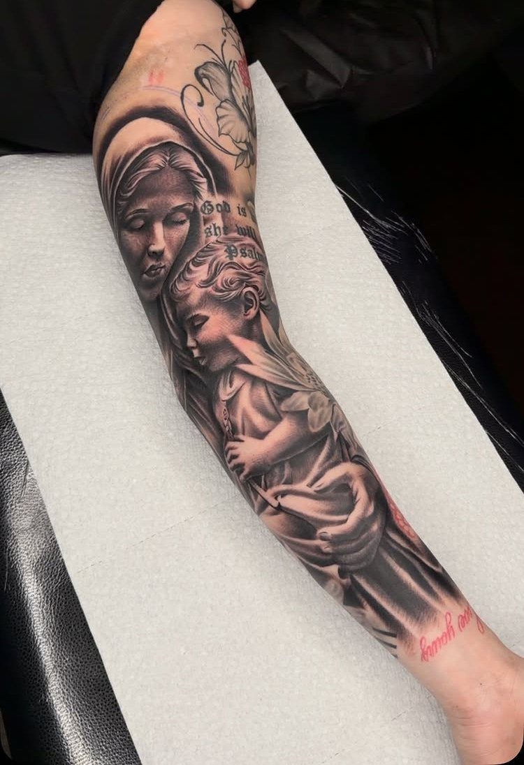 A large black and grey realism tattoo of a woman and child covering a person's arm.