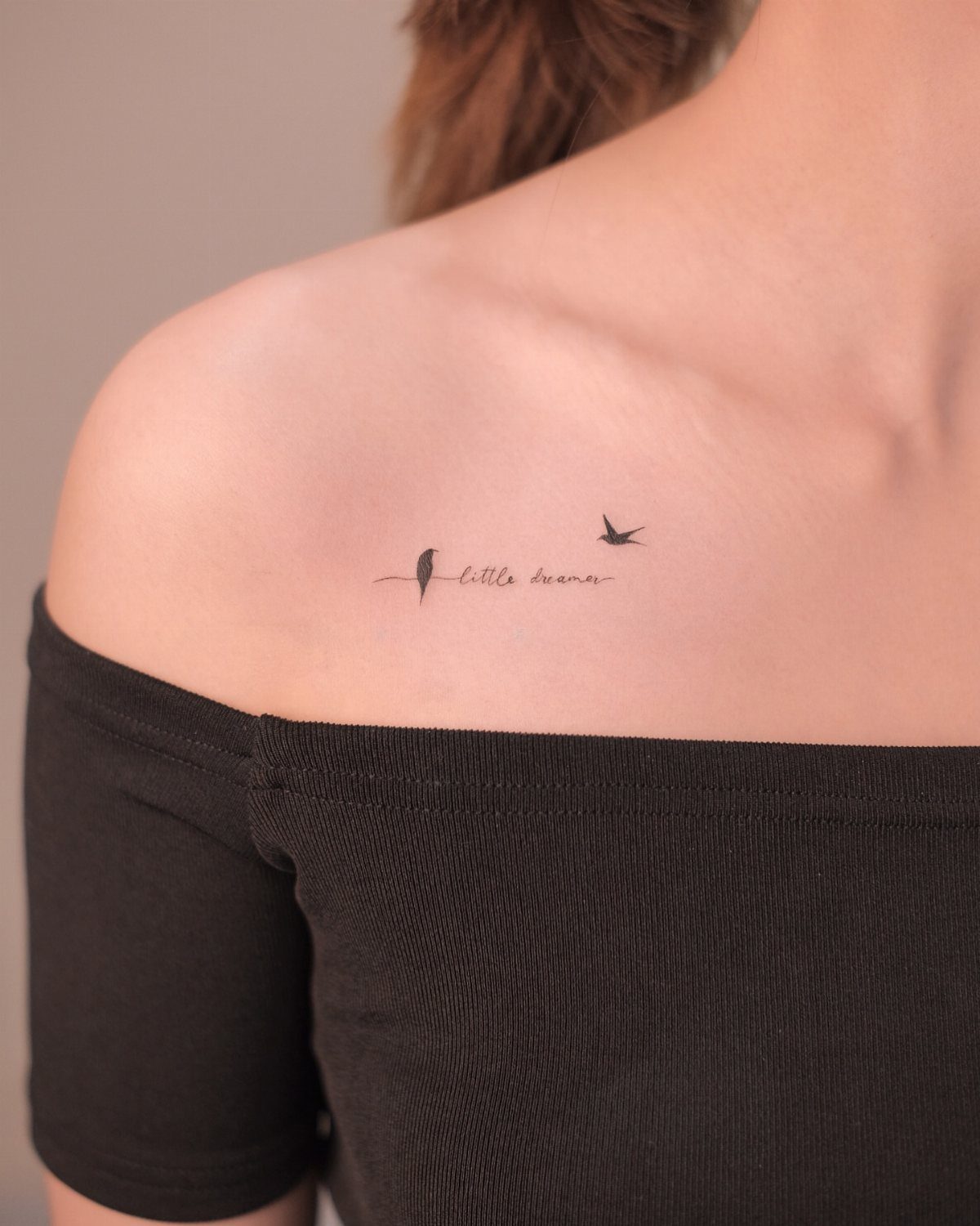 Tattoo Style Drawings: 6 Sketches Worth Keeping in Your Book 3 A minimalist black ink bird silhouette tattoo on a person's shoulder with cursive text.