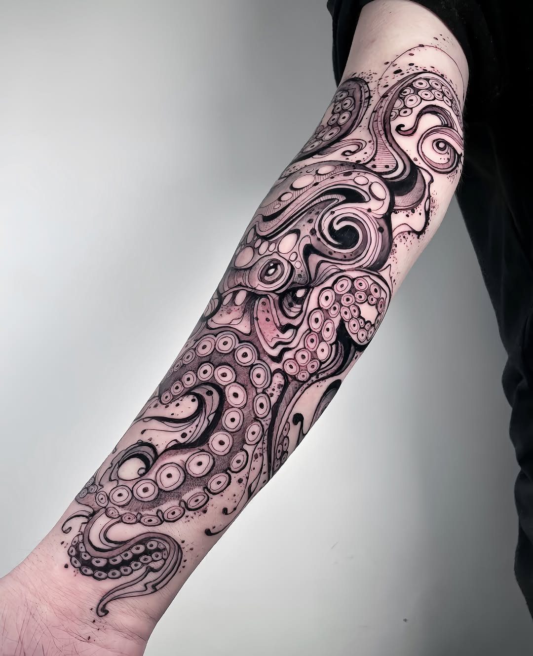 A detailed black and white octopus tentacle tattoo covering a person's entire forearm.