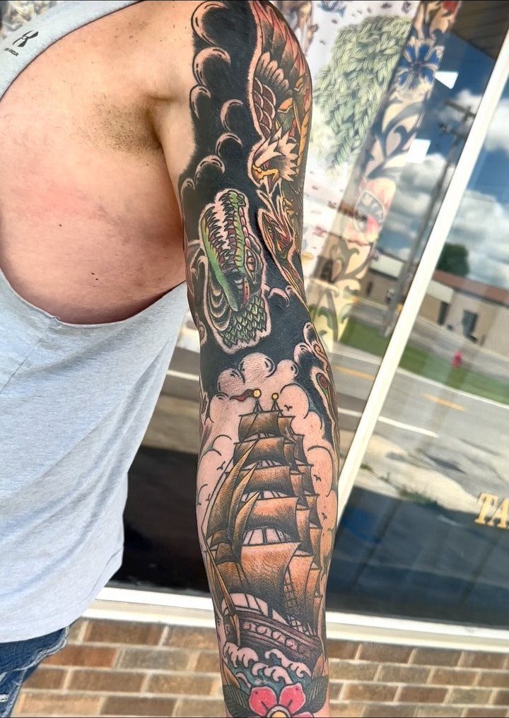 10 Traditional Cover Up Tattoo Ideas for Old Ink 3 A person's arm displaying a large, colorful traditional style tattoo sleeve with a ship.