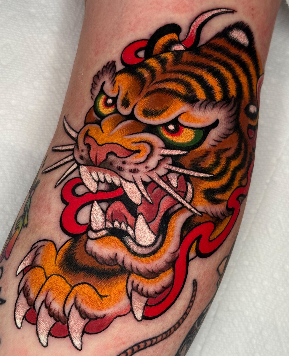 10 Traditional Cover Up Tattoo Ideas for Old Ink 9 A vibrant traditional tiger tattoo with orange and black stripes on a person's arm.